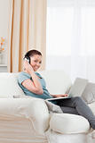Good looking woman with headphones relaxing with her laptop whil