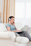 Beautiful woman with headphones relaxing with her laptop while s