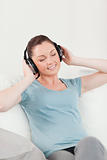 Lovely woman relaxing with headphones while sitting on a sofa