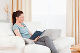 Cute woman reading a book while sitting on a sofa