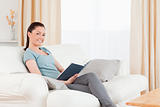 Beautiful woman reading a book while sitting on a sofa