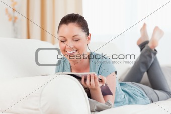 Lovely woman reading a magazine while lying on a sofa