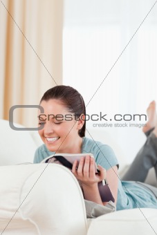 Beautiful woman reading a magazine while lying on a sofa