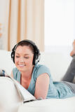 Attractive woman with headphones reading a magazine while lying 