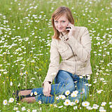 Beautiful young woman siting on a grass field in park and talkin