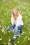 Beautiful young woman siting on a grass field in park and talkin