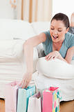 Charming woman touching her shopping bags while lying on a sofa
