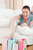 Attractive woman touching her shopping bags while lying on a sof