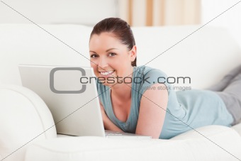 Good looking woman relaxing with her laptop while lying on a sof