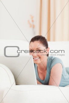 Beautiful woman relaxing with her laptop while lying on a sofa
