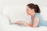 Side view of a beautiful woman relaxing with her laptop while ly