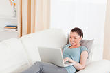 Lovely woman relaxing with her laptop while lying on a sofa