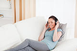 Beautiful female using headphones while lying on a sofa