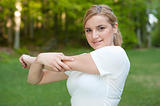 Attractive young woman stretches muscles in park