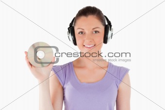 Good looking woman with headphones holding a CD while standing