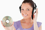 Attractive woman with headphones holding a CD while standing