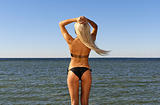 girl in a bikini turned her back and looks at the blue sea