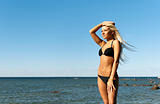girl in bikini posing on a rock near the sea