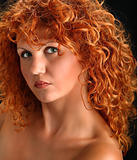Portrait of beautiful redhead woman with rich curly hair looking at camera