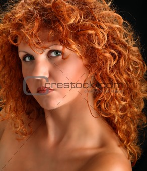 Portrait of beautiful redhead woman with rich curly hair looking at camera