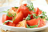 Ripe tomato salad with arugula in a rustic style on a wooden table