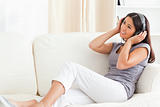 woman with earphones looking up sitting on sofa