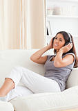 smiling woman with earphones looking up sitting on sofa