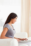 smiling woman sitting on sofa working with notebook