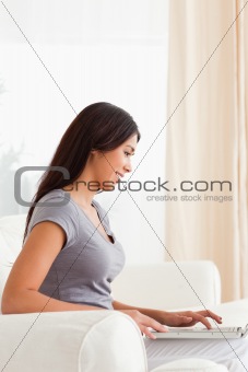 smiling woman sitting on sofa working with notebook
