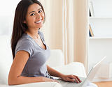 happy woman sitting on sofa with notebook looking into camera