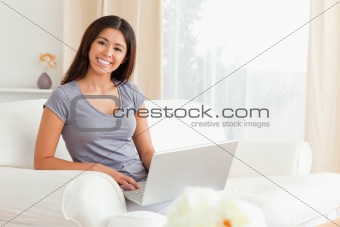cute woman sitting on sofa with notebook looking into camera