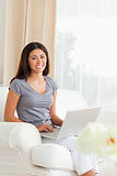 working woman sitting on sofa with notebook looking into camera