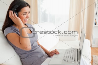 smiling woman sitting on sofa with notebook and earphones