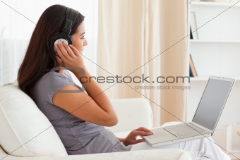 cute woman sitting on sofa with notebook and earphones