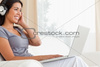 happy woman sitting on sofa with notebook and earphones