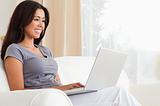 smiling woman sitting on sofa with notebook