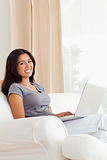 smiling woman sitting on sofa with notebook looking into camera