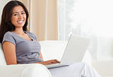 working woman sitting on sofa with notebook looking into camera