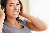 close up of smiling woman sitting on sofa with earphones looking