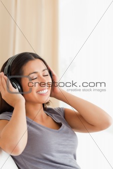 smiling woman sitting on sofa with earphones and eyes closed