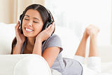 smiling woman lying on sofa with earphones eyes closed