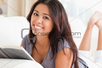 close up of a goodlooking woman lying on sofa reading a book loo