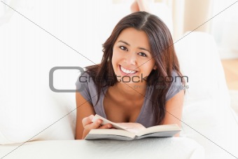 close up of a cute woman holding a book in her hand ans looking into camera