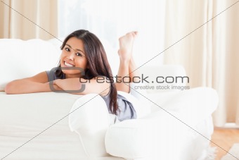 charming woman lying on sofa with crossed arms looking into came