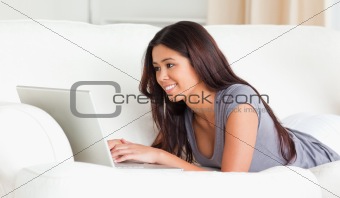 cute woman lying on sofa with notebook