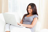 smiling woman sitting on sofa with laptop
