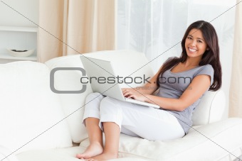 working lady with notebook on sofa smiling into camera