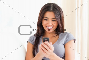 close up of a cheerful woman looking at mobile phone 