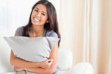 smiling woman with pillow in her arms looking into camera