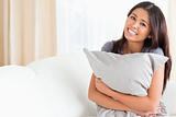 charming woman with pillow in her arms looking into camera